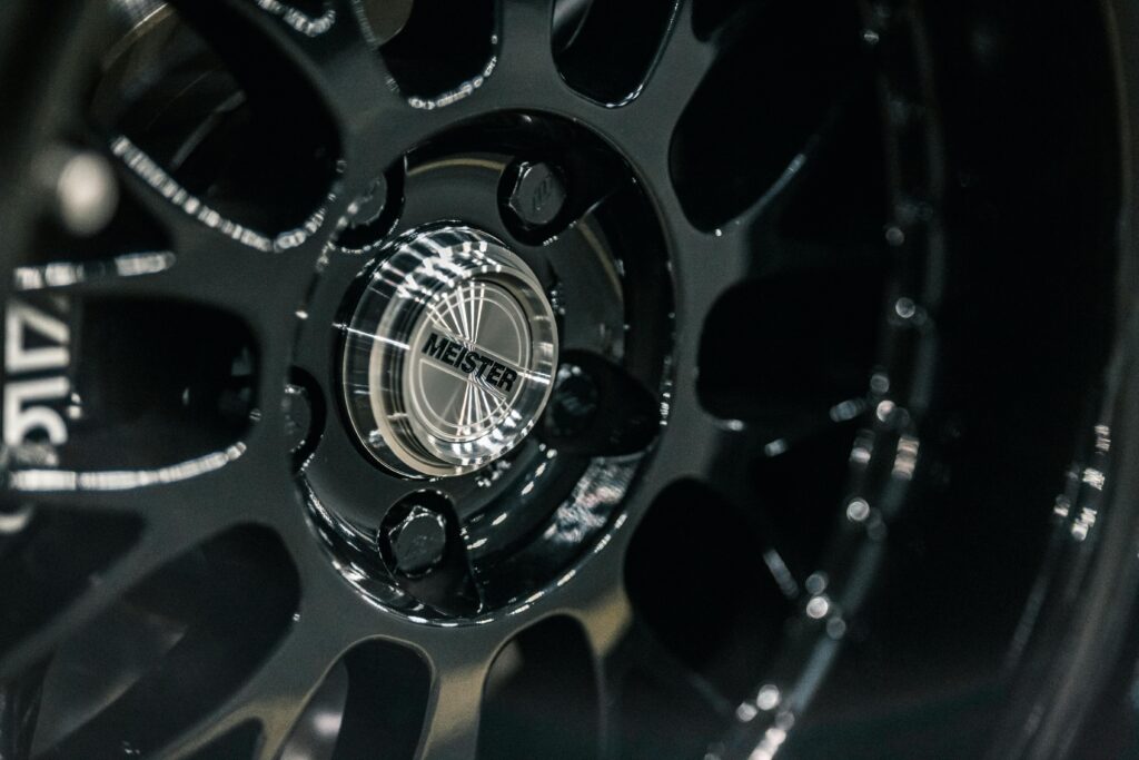 Small round glistening center cap with inscription on disk of modern car wheel with spokes